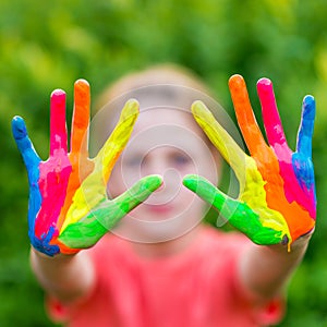 Little girl with hands painted in colorful paints ready for hand prints
