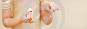 Little girl hands puling petals from a chamomile. Soft focus