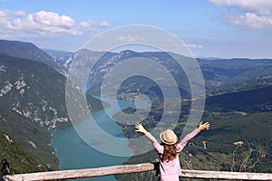 Little girl with hands up on mountain viewpoint