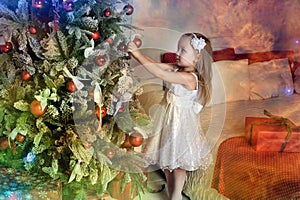Little girl hang on the Christmas tree toys