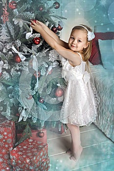 Little girl hang on the Christmas tree toys