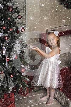 Little girl hang on the Christmas tree toys