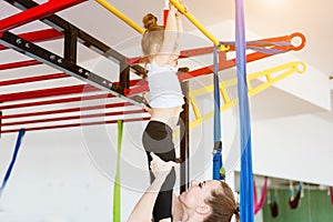 Little girl hanging on the crossbar, mom supports