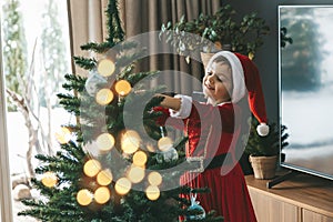 Little girl hanging ornaments and baubles on the Christmas tree