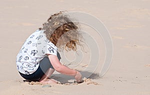 A little girl happily playing in the sand