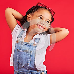 Little girl, happy and thinking in fashion pose, trendy or cool style clothes on isolated red background for kids