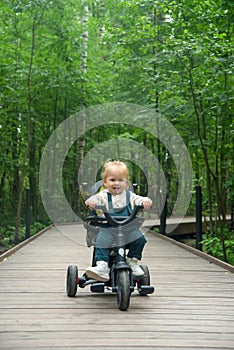 A little girl has fun riding a bike along a wooden path in the park