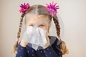 The little girl has runny nose and blowsnose into handkerchief.