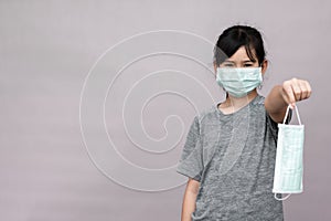 Little girl has sterile medical  mask protect herself from Coronavirus COVID-19 isolated on gray background.