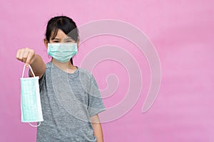 Little girl has sterile medical  mask protect herself from Coronavirus COVID-19 isolated on pink background.