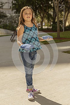 The little girl has a suspicious look while holding two bean bags, one on each hand