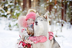 Little girl and hasky dog together in winter park