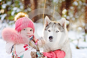 Little girl and hasky dog together in winter park