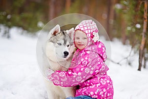 Little girl and hasky dog together in winter park