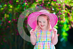 Little girl in a hat in blooming summer garden