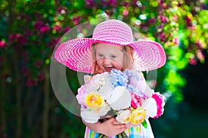 Little girl in a hat in blooming summer garden