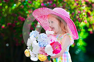 Little girl in a hat in blooming summer garden