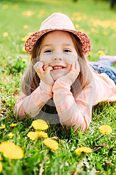 Little girl with hat lying on the grass