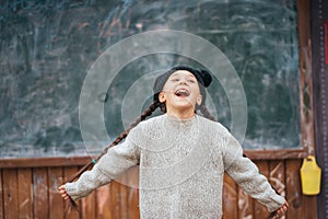 Little girl in a hat posing on the background of the school blackboard