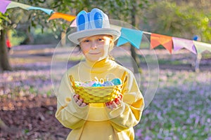 little girl in hat with rabbit ears o and basket with Easter eggs at party in park