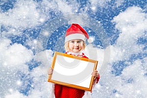 Little girl in hat of Santa Claus on background of sky