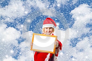 Little girl in hat of Santa Claus on background of sky