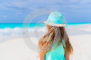 Little girl in hat walking at beach during caribbean vacation