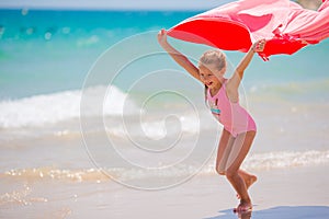 Little girl have fun with beach towel during tropical vacation