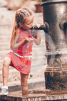 Little girl having fun with drinking water at street fountain in Rome, Italy