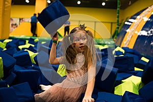 Little girl having fun in a dry pool with bright soft cubes to jump into. Kids playing room