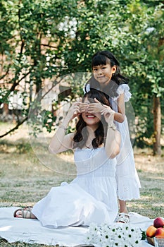 Little girl is having fun with her mother, covering her eyes with her palms