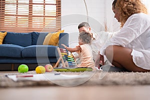 A little girl is having fun with her toys, and her mother is begging her daughter to sing