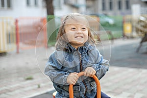 Little girl having fun on outdoor playground. Swinging on see-saw