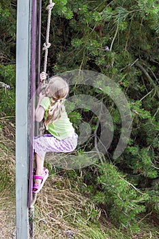 Little girl having fun outdoors at the climbing rope