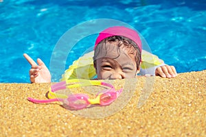 Little girl having fun in outdoors swimming pool.