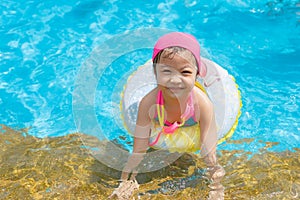 Little girl having fun in outdoors swimming pool.