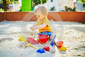 Little girl having fun on playground in sandpit