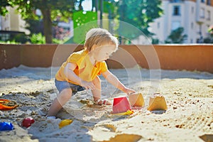 Little girl having fun on playground in sandpit