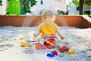 Little girl having fun on playground in sandpit