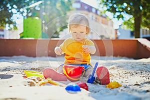 Little girl having fun on playground in sandpit