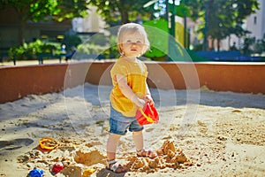 Little girl having fun on playground in sandpit