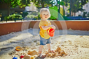 Little girl having fun on playground in sandpit