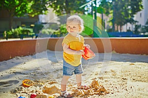 Little girl having fun on playground in sandpit