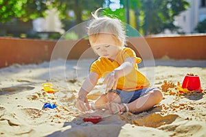 Little girl having fun on playground in sandpit