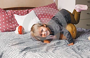 Little girl having fun playing at home on the bed with a big pumpkin