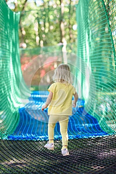 Little girl having fun at a rope playground. The girl is playing on net ropes.