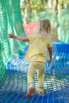 Little girl having fun at a rope playground. The girl is playing on net ropes.