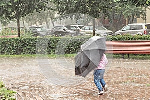 A little girl is having fun running around with an umbrella in the heavy rain. Rainy day