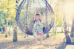 Little girl is having fun on a swing in city park