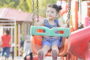 Little girl having fun on swing in outdoors area